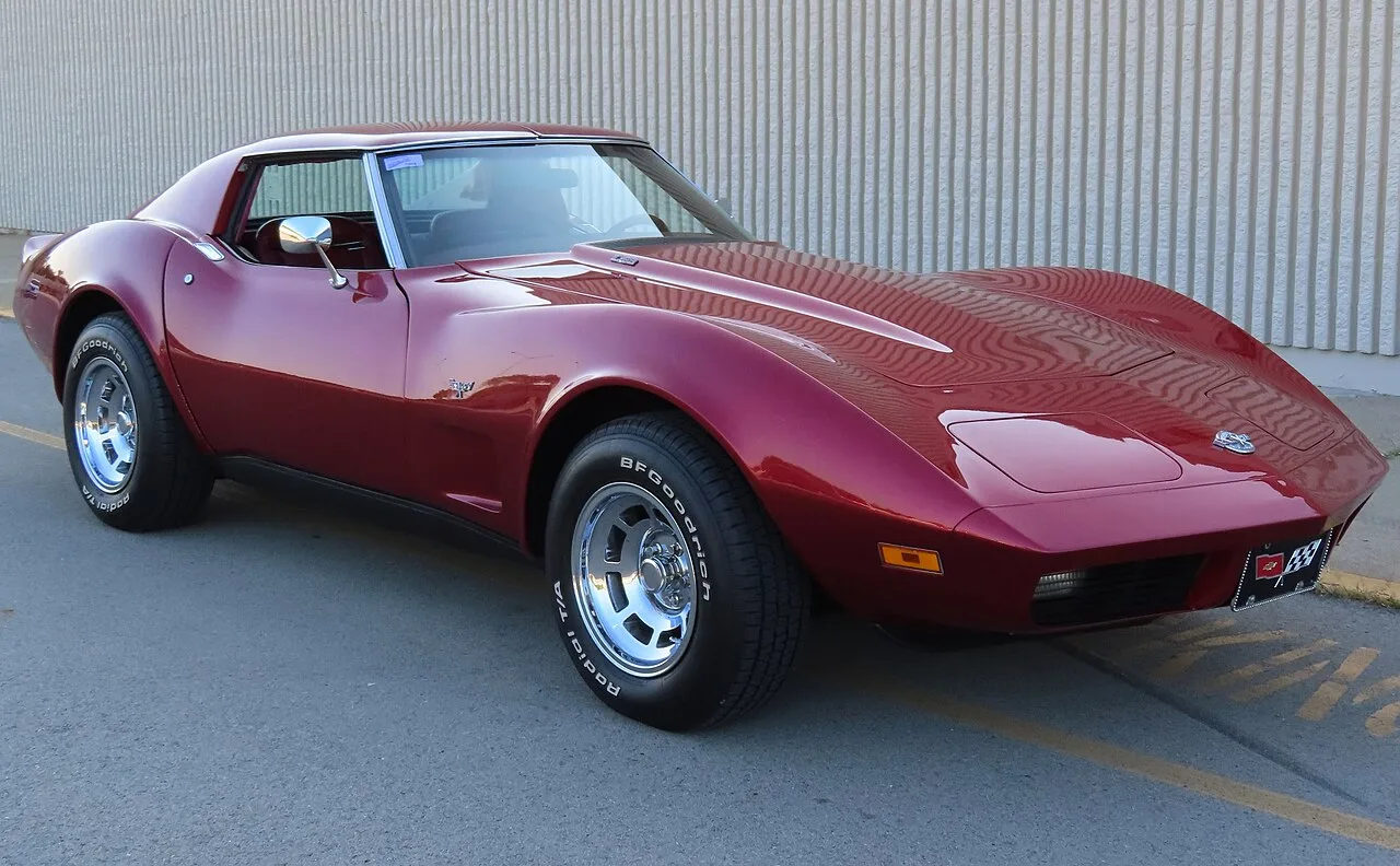 Een donkerrode Chevrolet Corvette C3 met het kenmerkende sharknose-design en lange motorkap
