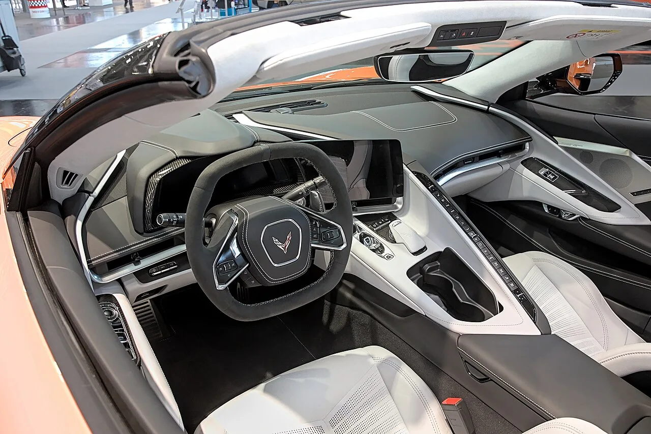 Rode Chevrolet Corvette C8 Convertible met neergelaten elektrische hardtop op een bergweg in zonlicht
